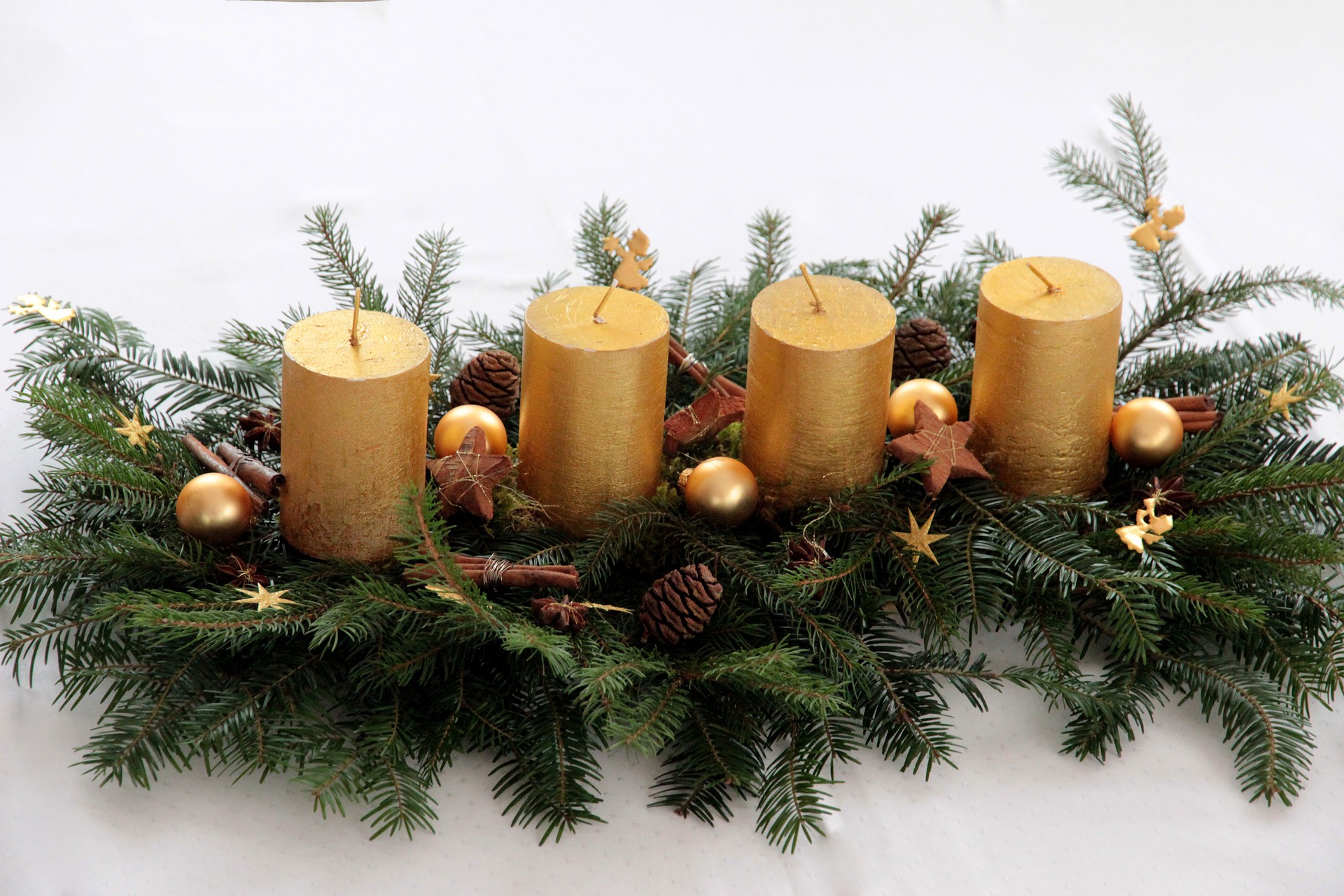 Adventsdekoration med guld lys og pynt med kogler og guld kugler